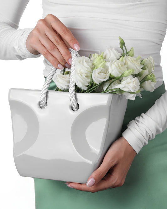 Gray ceramic handbag vase with rope handles filled with flowers, modern minimalist home decor