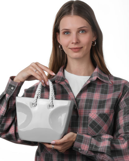 Gray handbag-shaped ceramic vase with rope handles held in hand, minimalist aesthetic flower vase