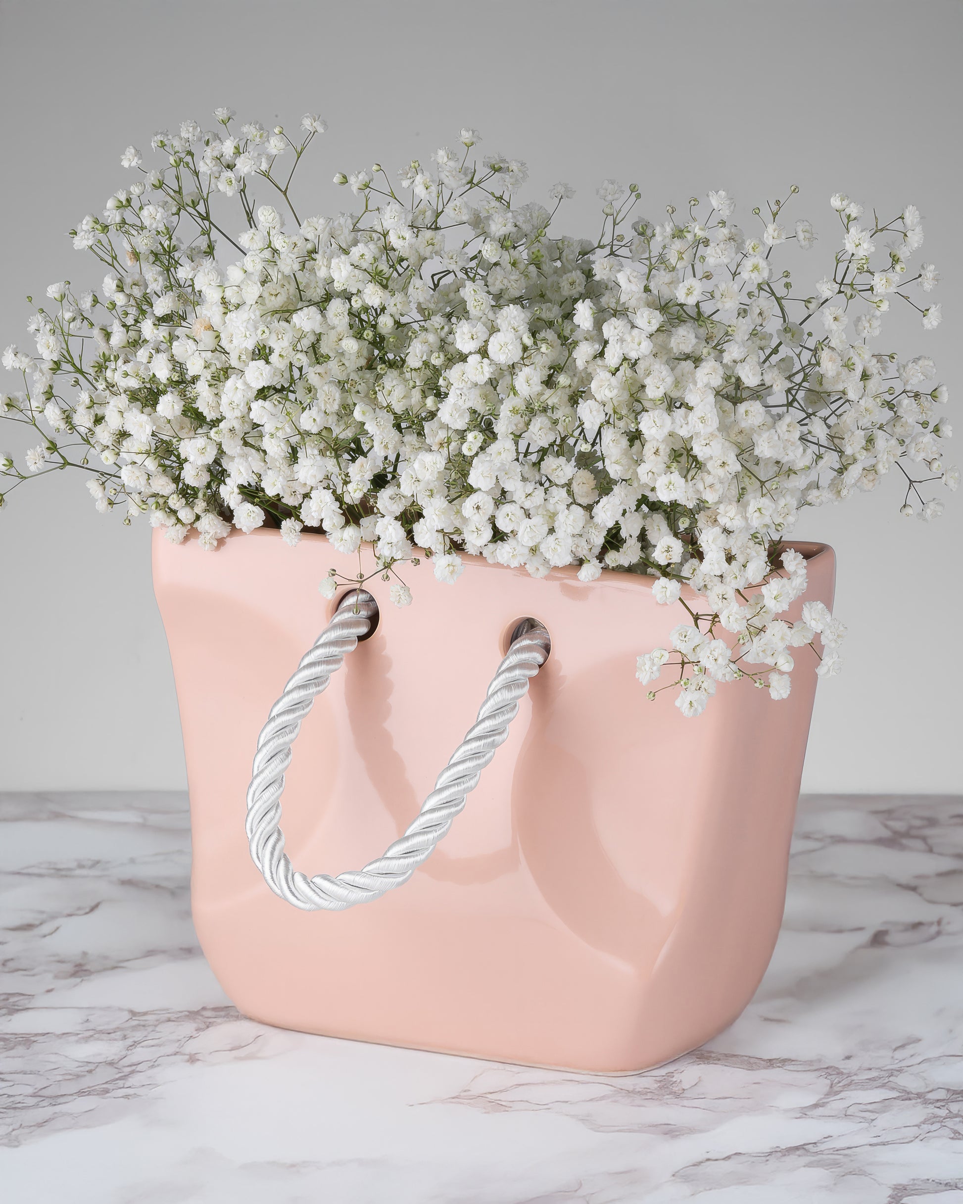 Beige ceramic handbag vase filled with dried stems, organic modern decor piece