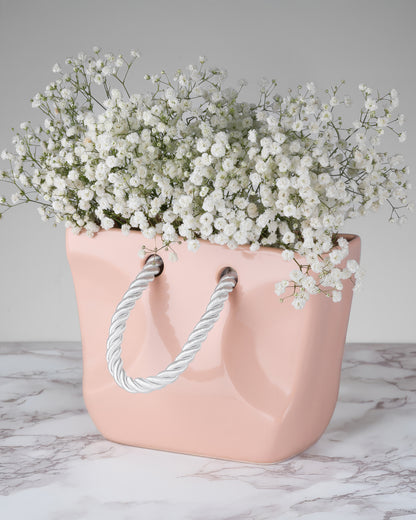 Beige ceramic handbag vase filled with dried stems, organic modern decor piece