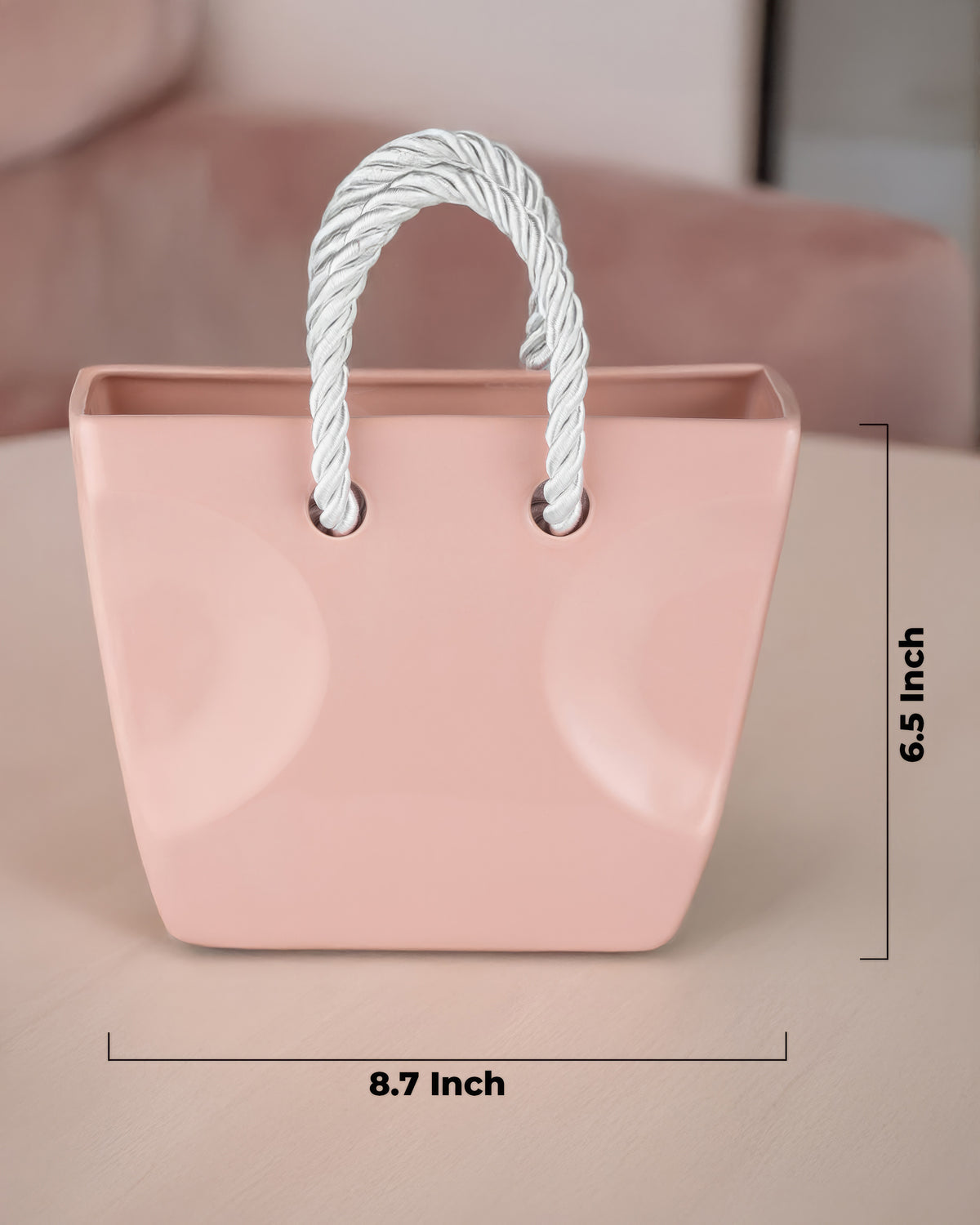 Beige ceramic purse vase with twisted rope handles on a neutral surface, japandi home decor