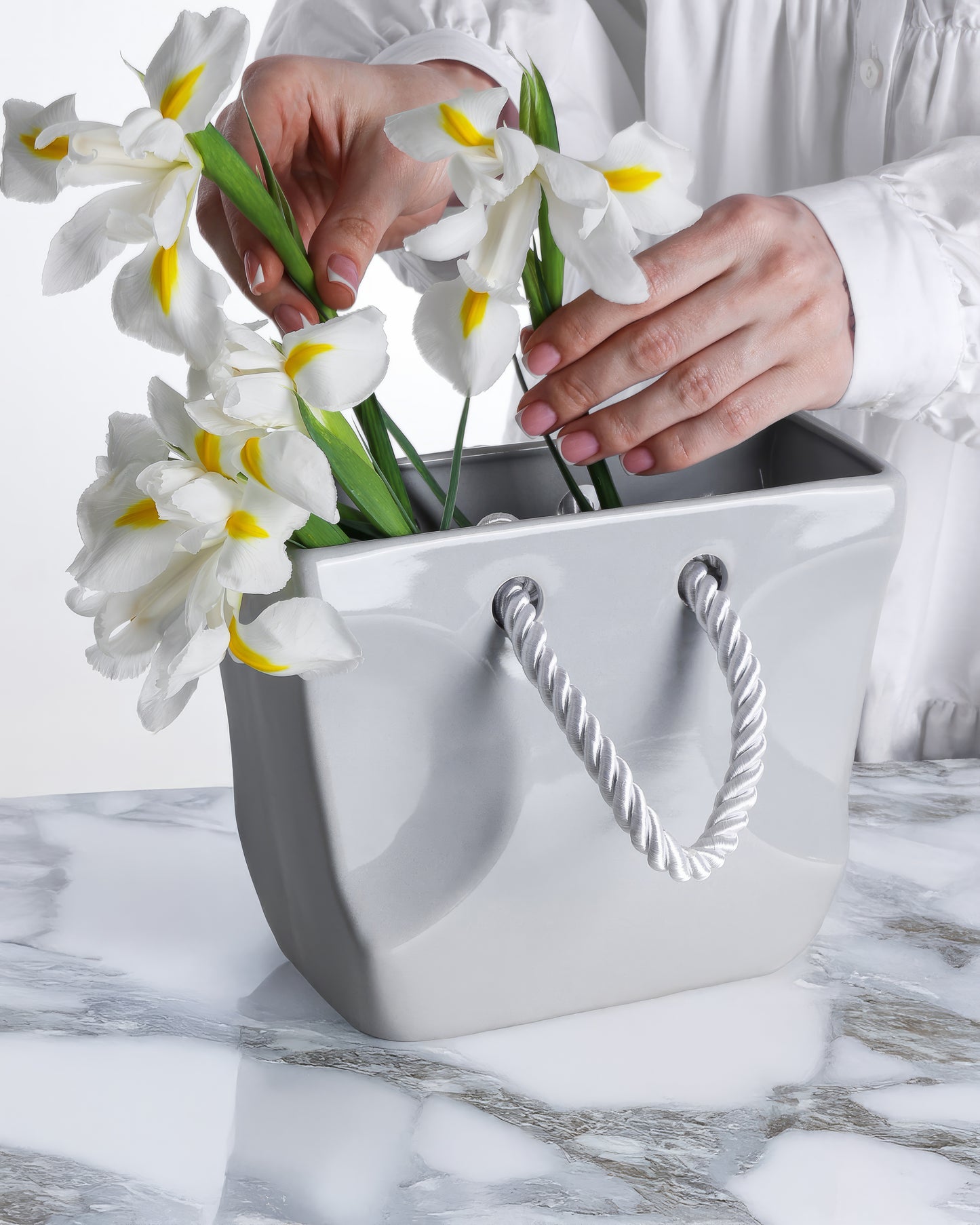 Gray ceramic handbag vase styled with a single sculptural stem as modern minimalist decor